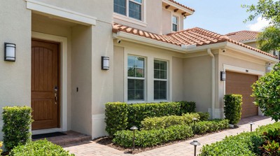 Florida home exterior with security-focused landscaping, outdoor lighting, and a smart lock on the front door
