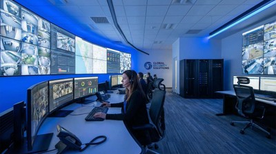 Professional alarm monitoring center operator viewing multiple security screens and dashboards